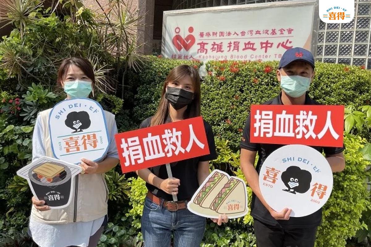 喜得除了堅持創新之外，也持續回饋社會各角落，傳遞溫暖，關懷珍愛這片土地。圖片有一男一女舉的捐血救人的牌子，另外一個人舉著喜得的手拿牌。